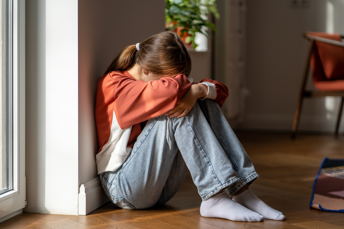 Upset Depressed Teenage Girl Sitting Alone on Floor and Crying